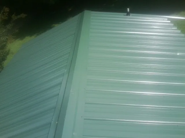 New green metal panels meeting at the ridge of a roof — Flat Roof Repair work by our crew in Terreton