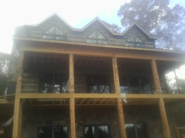 Dormers and porch framing on a large log home under construction — Roof Coating work by our crew in Terreton