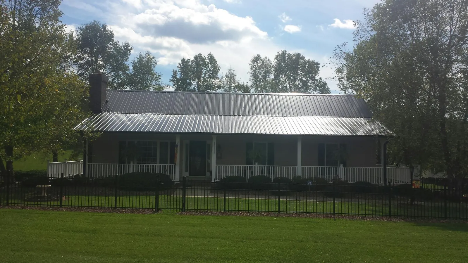 Gray metal roof on a brick ranch with a full width front porch — Gutter Guard Installation work by our crew in Terreton