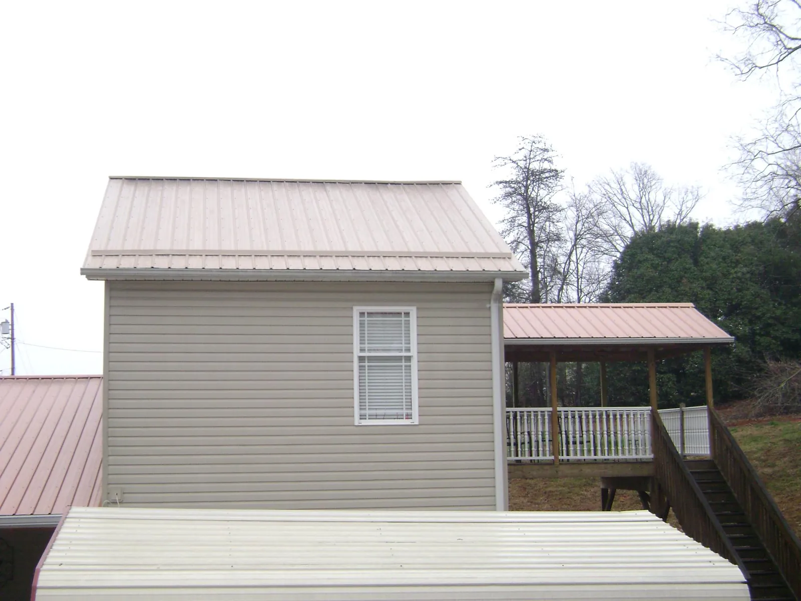 Tan metal roofs on a two story addition and attached porch, from a Roof Replacement job in Terreton